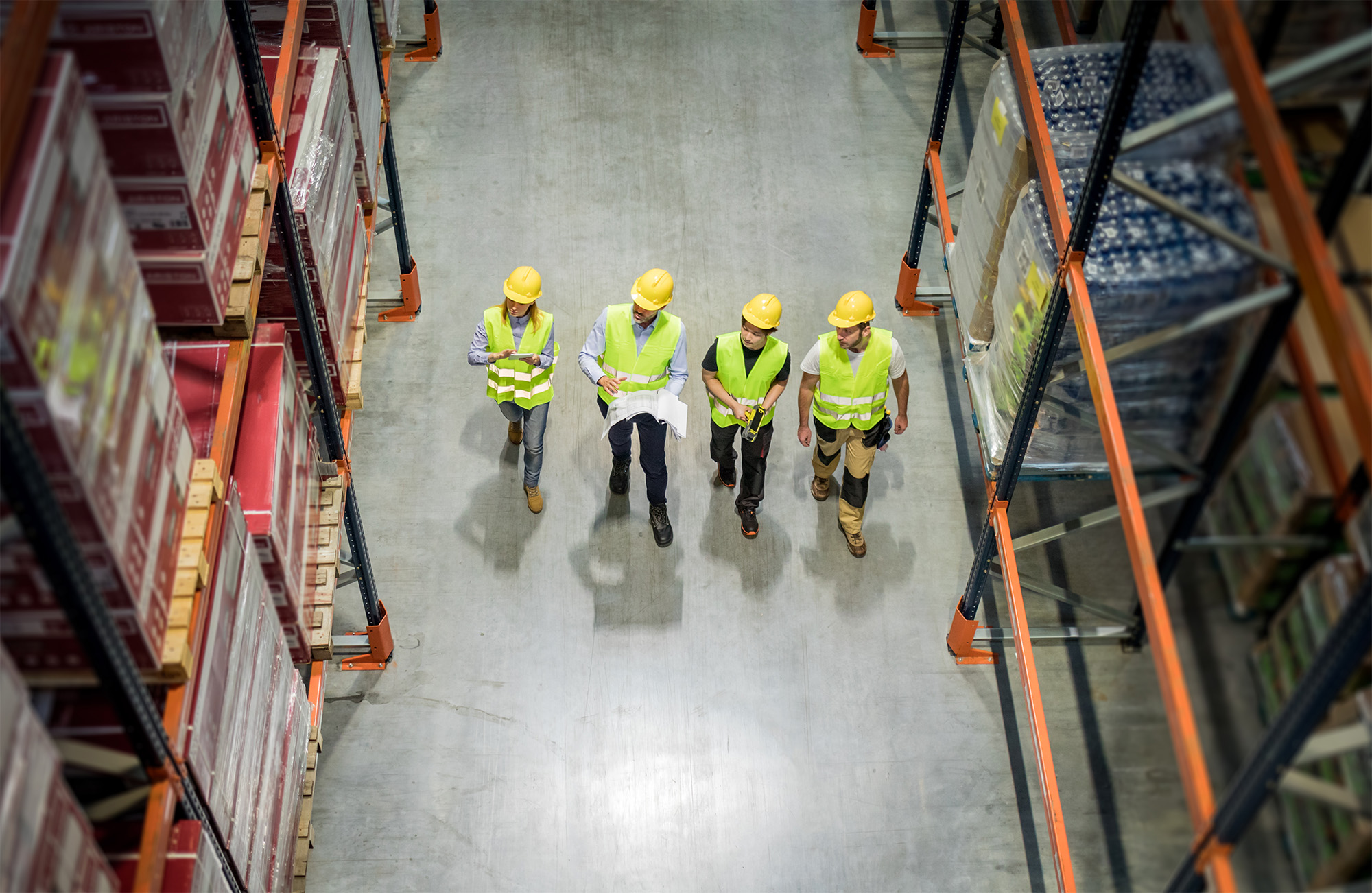 Warehouse workers at work between rows of tall shelves full of packed boxes